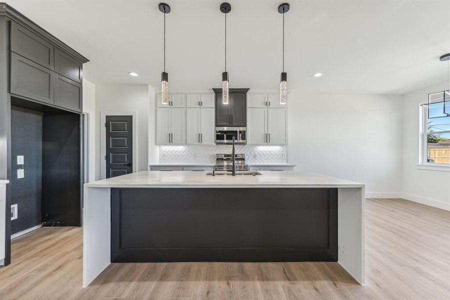 Kitchen with hanging light fixtures, appliances with stainless steel finishes, and light hardwood / wood-style flooring