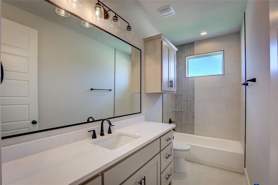 Full bathroom featuring tiled shower / bath, tile flooring, oversized vanity, and toilet