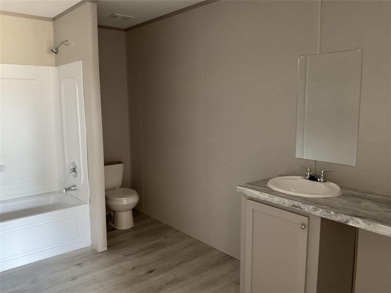 Full bathroom featuring vanity, crown molding, shower / bathtub combination, hardwood / wood-style flooring, and toilet