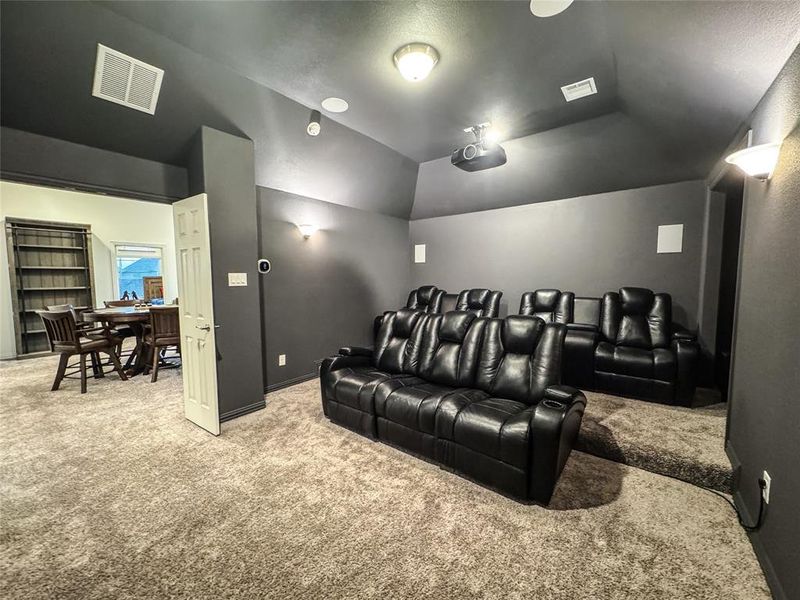 Carpeted cinema room featuring lofted ceiling