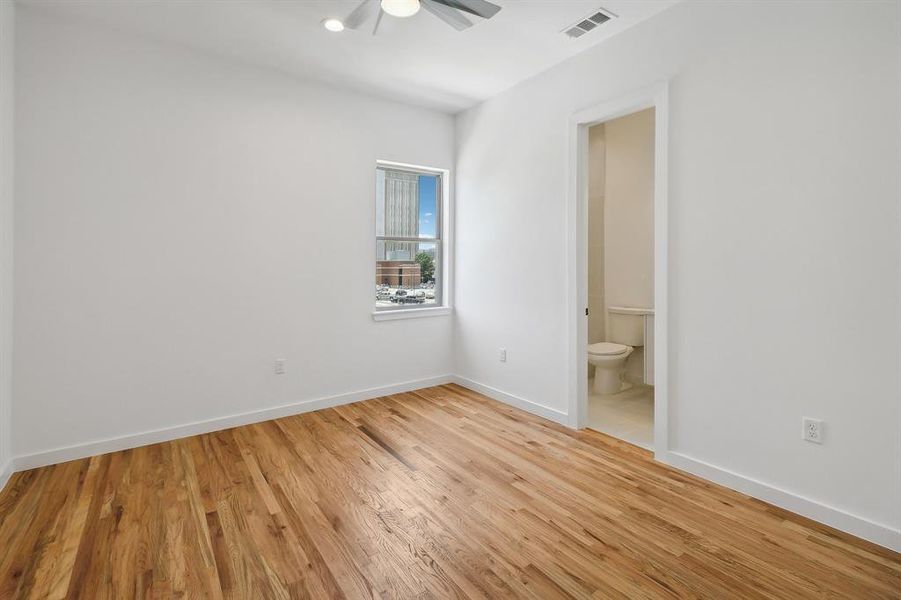 Unfurnished bedroom featuring light hardwood / wood-style floors, ensuite bathroom, and ceiling fan