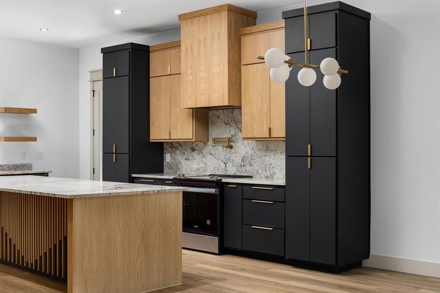 Kitchen featuring light stone countertops, light hardwood / wood-style flooring, a center island, and stainless steel range oven