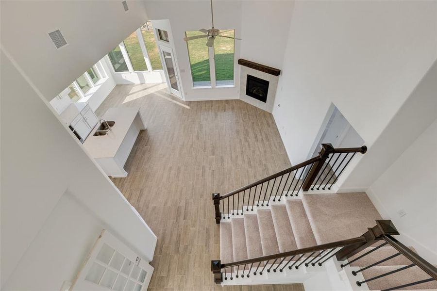 Stairway featuring ceiling fan, hardwood / wood-style floors, a towering ceiling, a tile fireplace, and sink