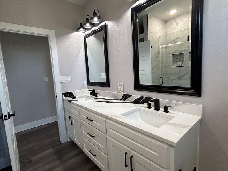 Bathroom featuring a shower with door, hardwood / wood-style flooring, and vanity