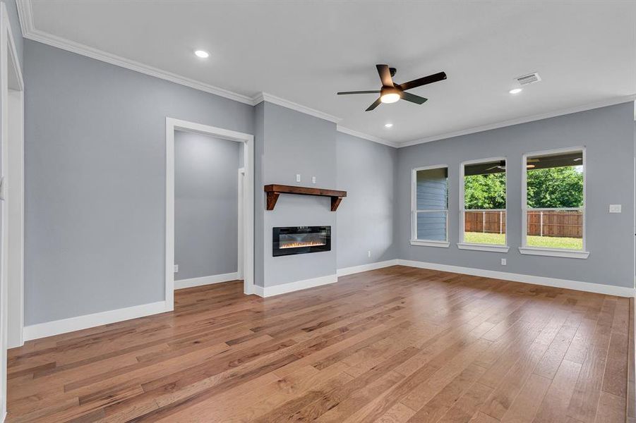 Unfurnished living room featuring ceiling fan, light hardwood / wood-style flooring, and ornamental molding