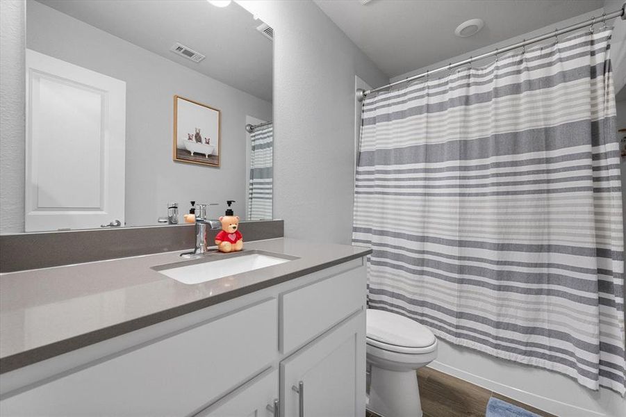 Upstairs full bathroom featuring shower / tub combo, hardwood / wood-style floors, vanity, and toilet