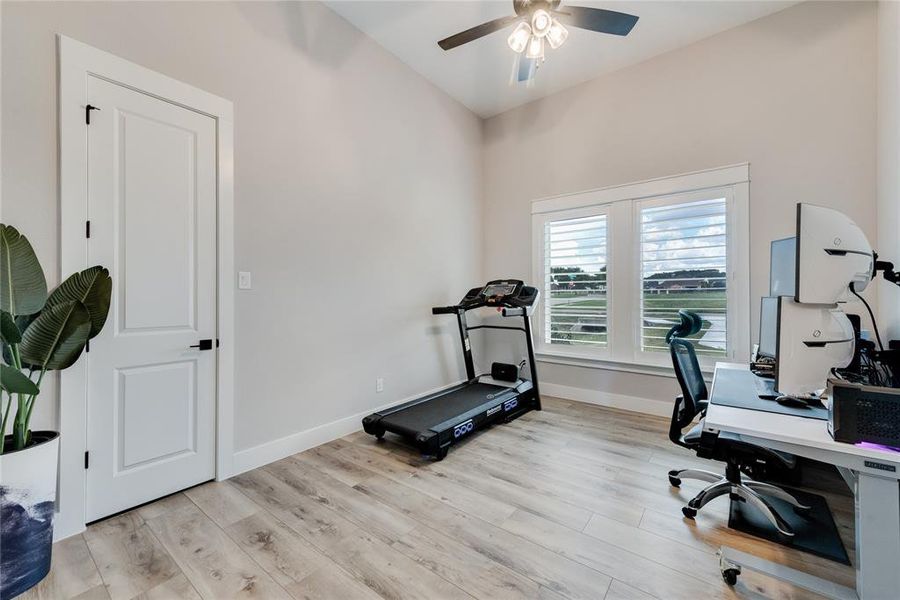 Exercise area with ceiling fan and light wood-type flooring