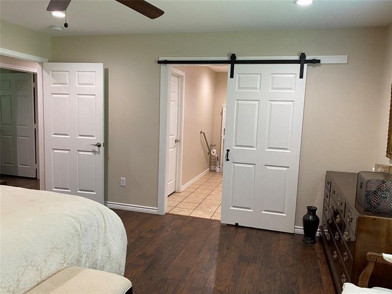 Primary Bedroom featuring a barn door, ceiling fan, and hardwood / wood-style floors