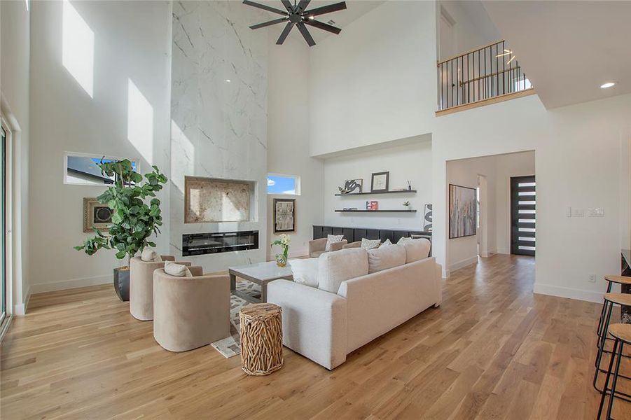 Living room featuring a large fireplace, a wealth of natural light, a high ceiling, and light hardwood / wood-style floors