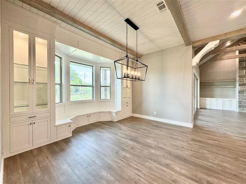 Unfurnished dining area with hardwood / wood-style floors, a chandelier, and beam ceiling