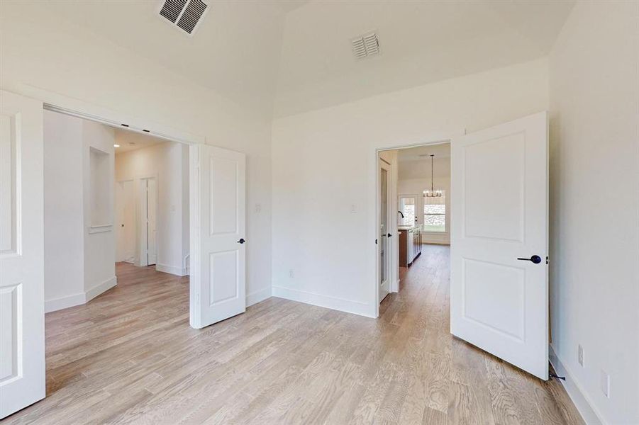 Empty room with light hardwood / wood-style flooring and an inviting chandelier