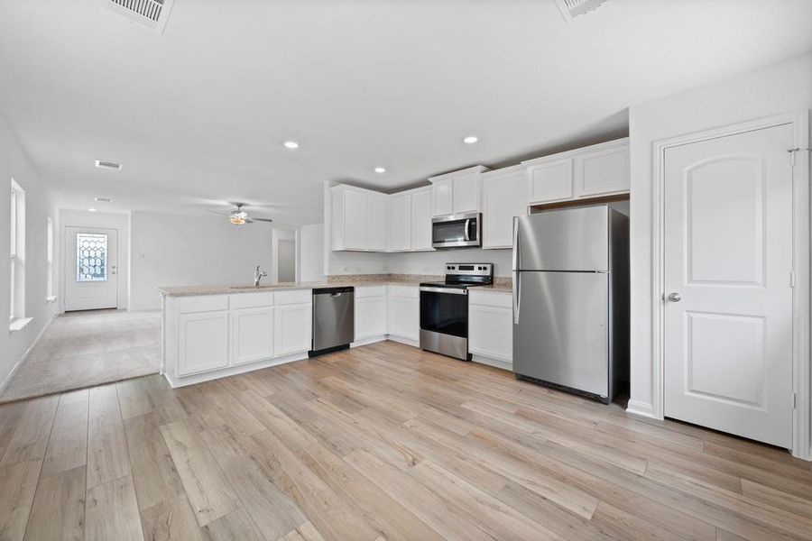 Kitchen includes granite countertops, luxury vinyl plank flooring, 36” upper cabinets with crown molding, a full suite of stainless-steel Whirlpool appliances – including refrigerator with ice maker, recessed lighting, and a large single basin sink.