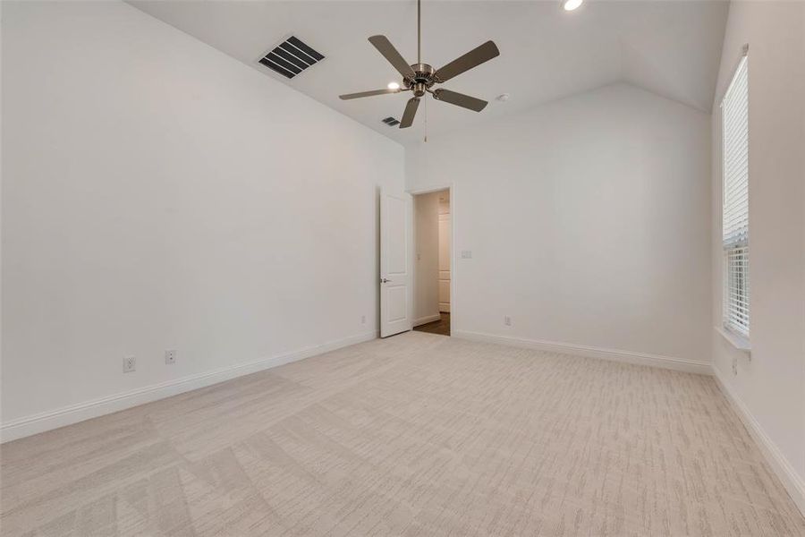 Empty room featuring light carpet, ceiling fan, and high vaulted ceiling