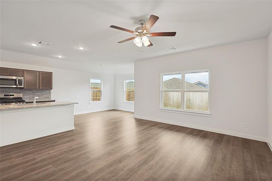 Unfurnished living room featuring dark hardwood / wood-style floors, sink, and ceiling fan