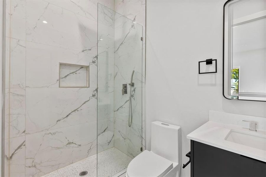 Bathroom featuring vanity, toilet, and a shower with door