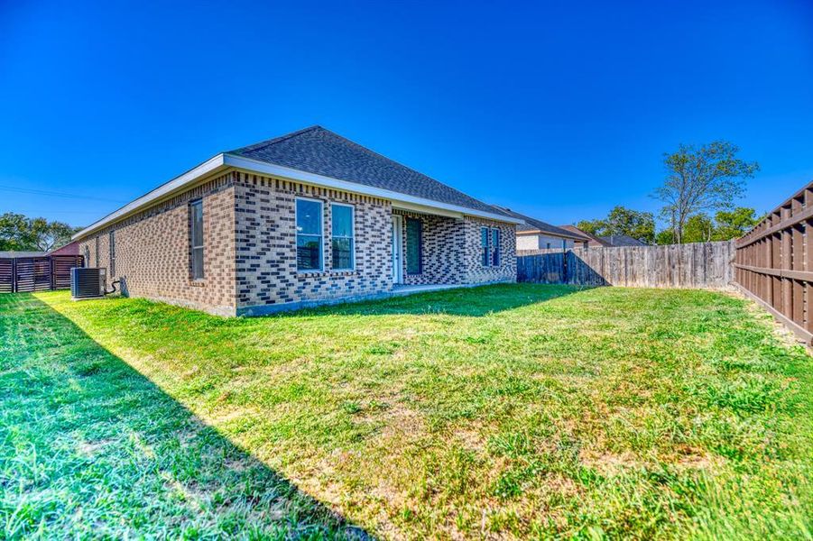 Back of house with central AC and a lawn