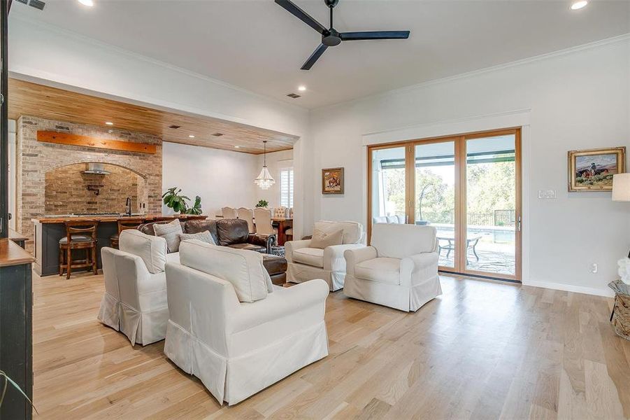 Spacious and bright, featuring large windows, custom shutters, and a seamless connection to the outdoor patio through accordion doors.