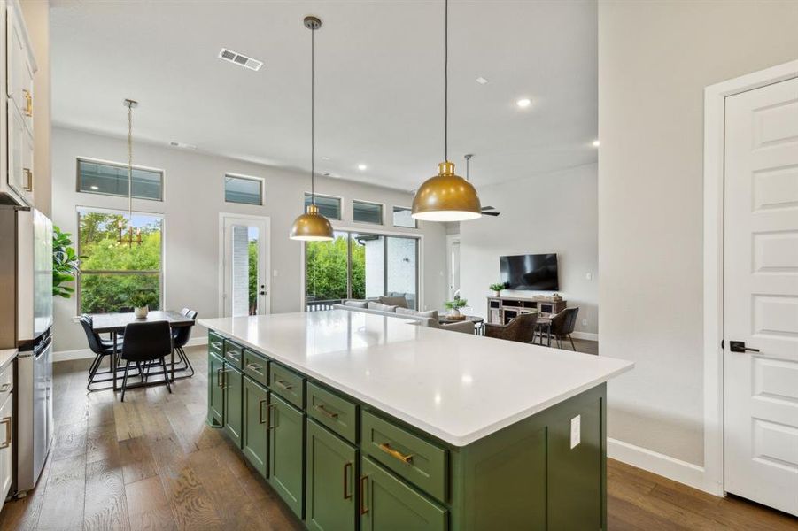 Kitchen with pendant lighting, stainless steel fridge with ice dispenser, a center island, dark wood-type flooring, and green cabinetry