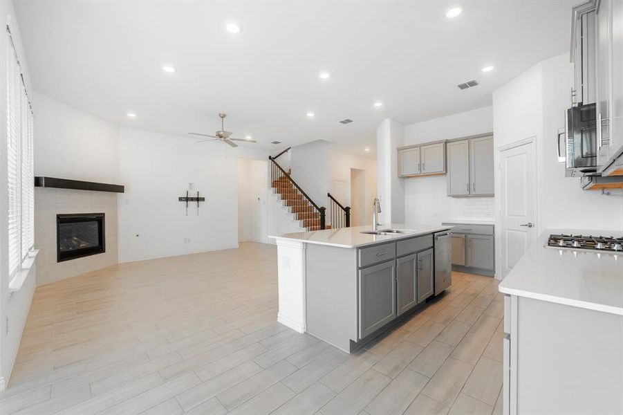 Kitchen featuring sink, an island with sink, ceiling fan, light hardwood / wood-style floors, and gray cabinets