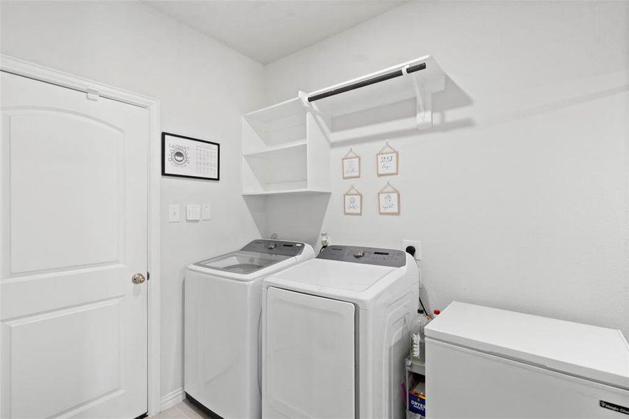 Spacious laundry room equipped with refrigerator hook-up and ample under-stair storage.