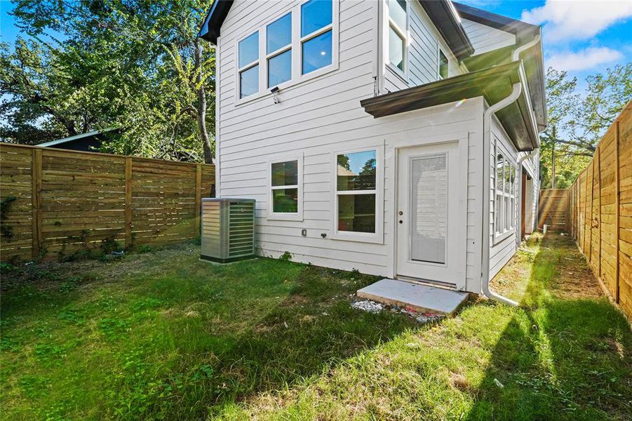 Rear view of house with a yard and central air condition unit