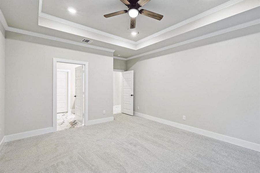 Unfurnished bedroom with crown molding, a raised ceiling, and light colored carpet