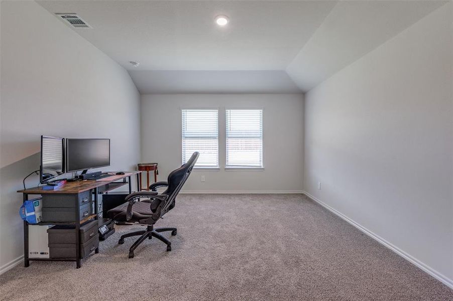 Carpeted office featuring lofted ceiling