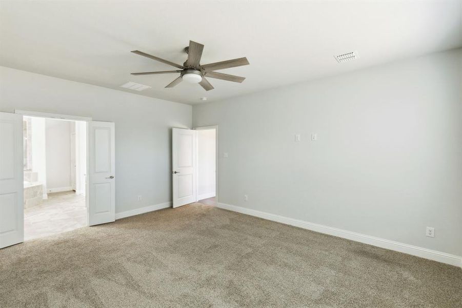 Unfurnished bedroom with ensuite bath, ceiling fan, and light carpet