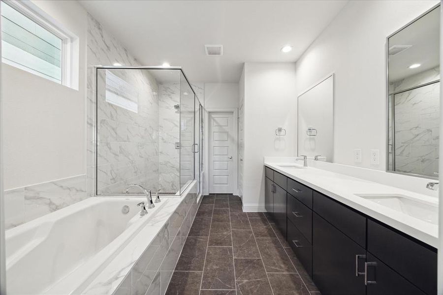 This luxurious primary bathroom features a sleek, modern design. The double vanity offers ample storage and counter space, while the oversized soaking tub invites relaxation.