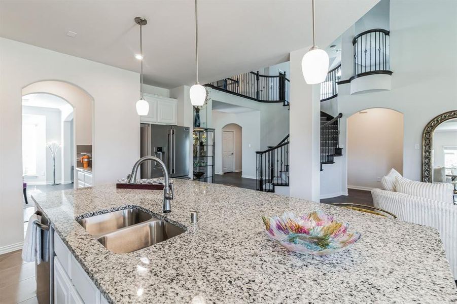 Kitchen with white cabinets, light stone countertops, appliances with stainless steel finishes, a towering ceiling, and sink