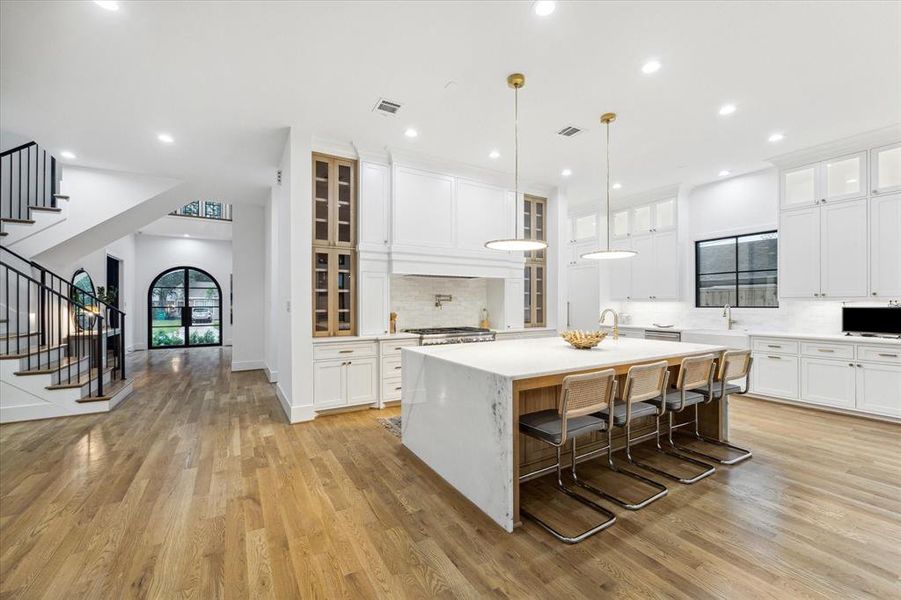 This kitchen! Statement island with waterfall Dolomite countertop, accented with designer pendents. The white oak island offers tons of storage, a prep sink and lots of space for your favorite counter stools for your favourite people!