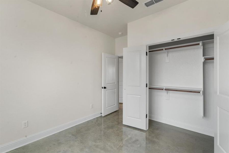 Unfurnished bedroom with concrete flooring, ceiling fan, and a closet