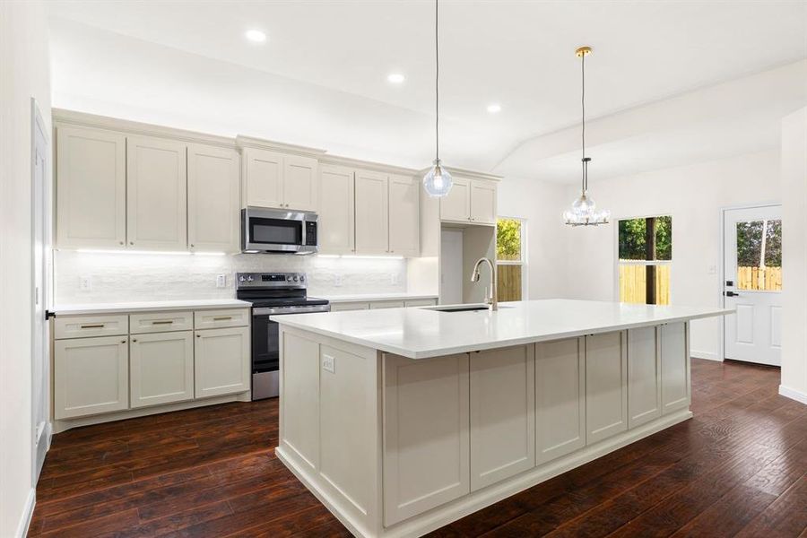 Kitchen featuring dark hardwood / wood-style flooring, a kitchen island with sink, stainless steel appliances, decorative backsplash, and pendant lighting