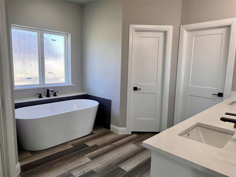 Bathroom with hardwood / wood-style floors, a tub, and vanity