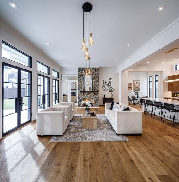 Spacious family room with elegant hanging chandelier, fire place, Engineered French Oak hardwood floors and wall of french doors leading to the outdoor deck and yard