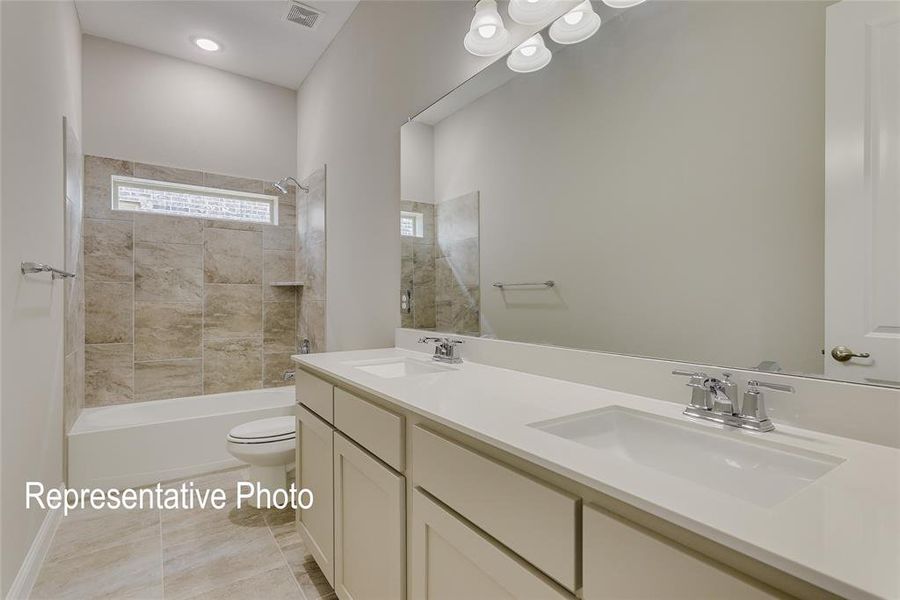 Full bathroom featuring toilet, tiled shower / bath, vanity, and tile patterned floors