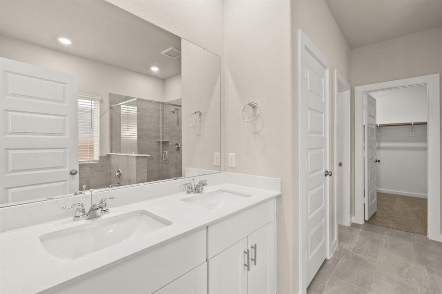 The Primary Bath Oasis features dual sinks with extended countertop, glass encased walk-in shower with tile surround, separate soaking tub and modern finishes throughout.