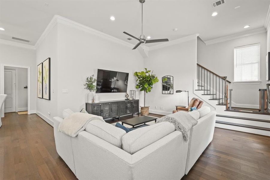 Arrive and be mesmerized at this incredible living room! Highlighting engineered wood floors, crown molding details, recessed lighting, and a ceiling fan.