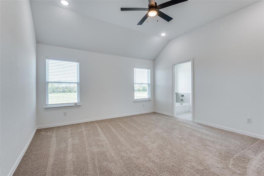 Spare room featuring light carpet, vaulted ceiling, and ceiling fan