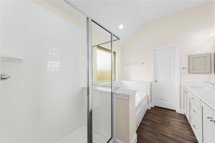 Bathroom featuring lofted ceiling, hardwood / wood-style floors, separate shower and tub, and vanity