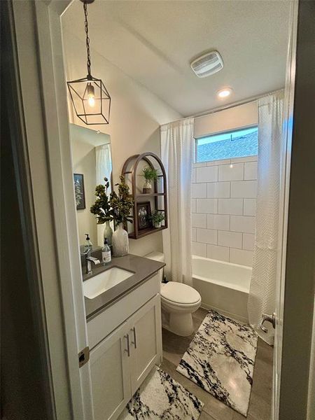 Full bathroom with tile patterned flooring, shower / bathtub combination with curtain, vanity, and toilet