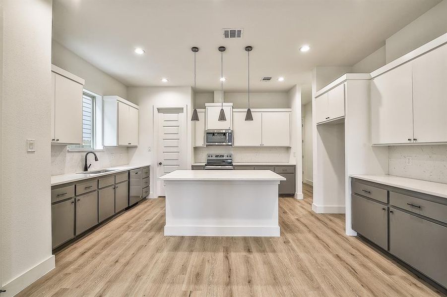 Kitchen with a kitchen island, sink, appliances with stainless steel finishes, white cabinets, and light hardwood / wood-style floors