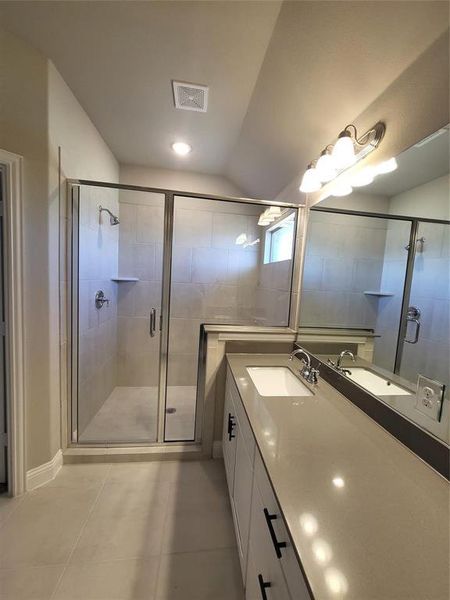 Bathroom featuring lofted ceiling, vanity, a shower with shower door, and tile patterned flooring