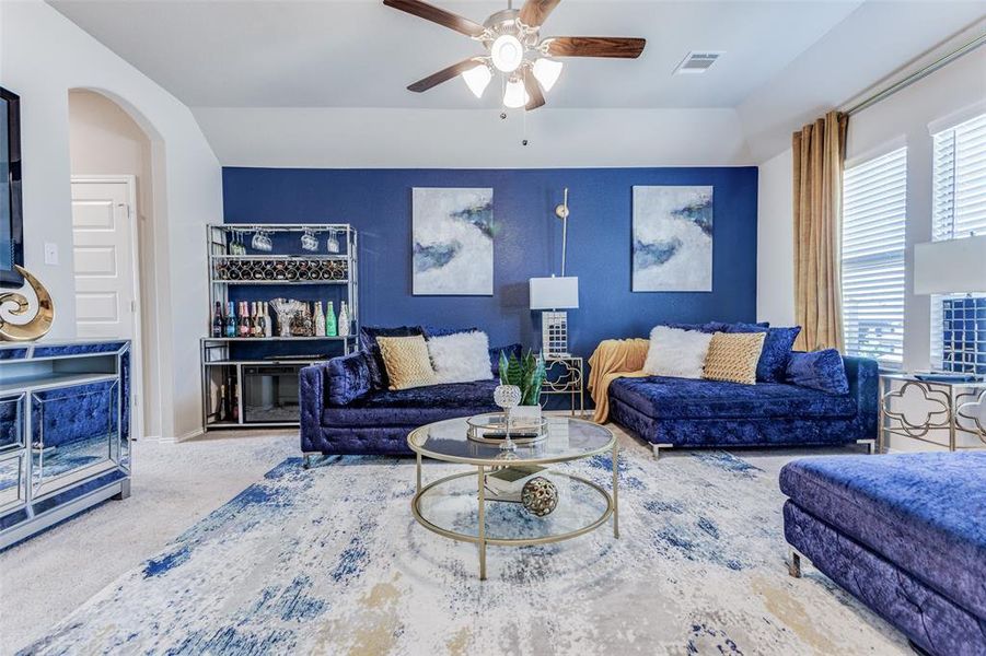 Living room featuring carpet floors, a fireplace, and ceiling fan