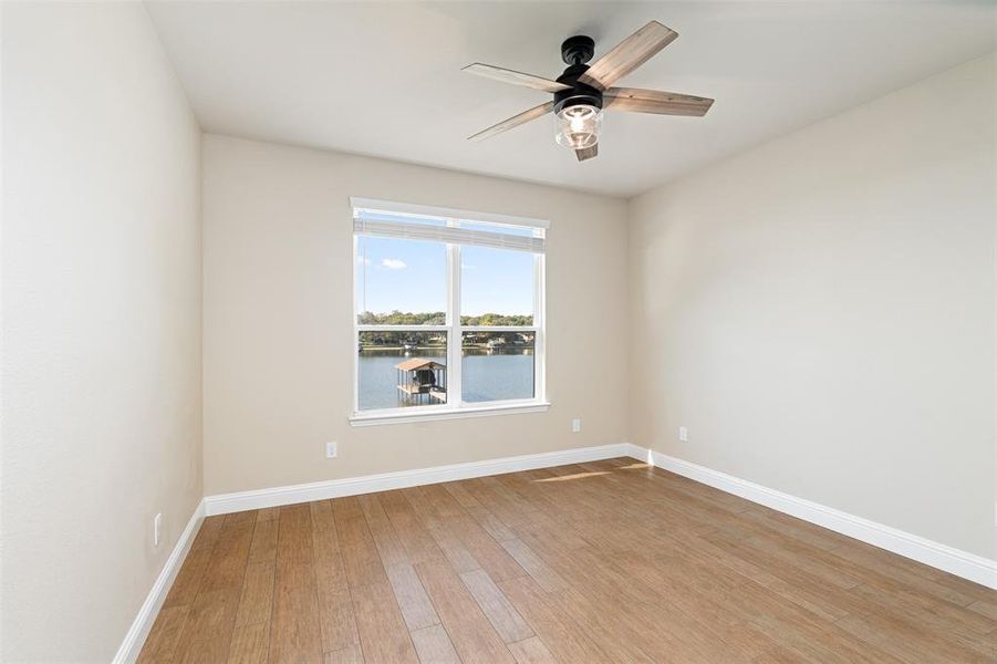 Unfurnished room with a water view, hardwood / wood-style flooring, and ceiling fan