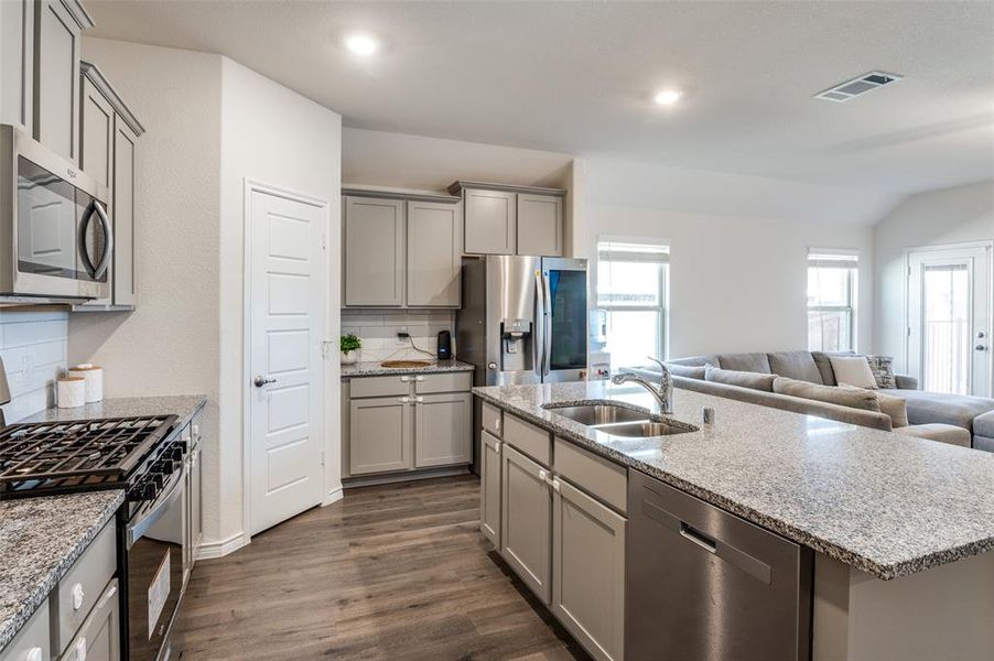 Kitchen featuring a center island with sink, appliances with stainless steel finishes, sink, decorative backsplash, and dark hardwood / wood-style floors