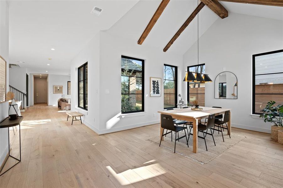 Dining space with high vaulted ceiling, beamed ceiling, and light hardwood / wood-style flooring