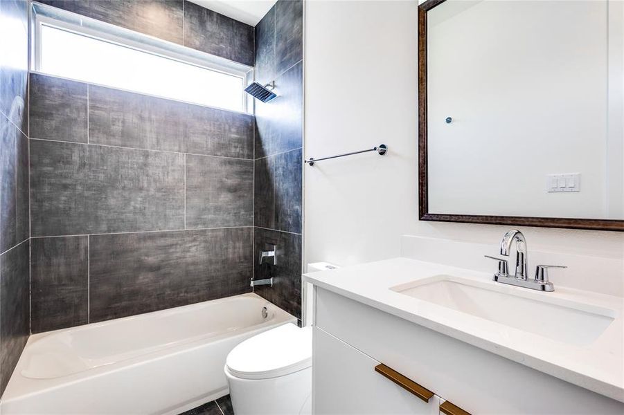 Full bathroom with tiled shower / bath, vanity, a wealth of natural light, and toilet