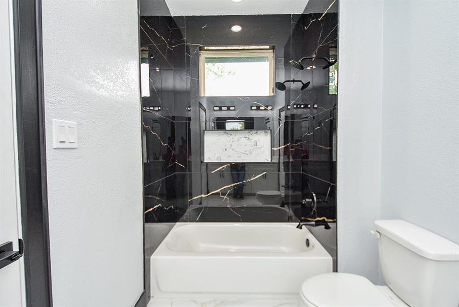 This bathroom features a bathtub and shower combination and serves two adjacent rooms. Additionally, it includes an inset shower niche for added functionality and style.