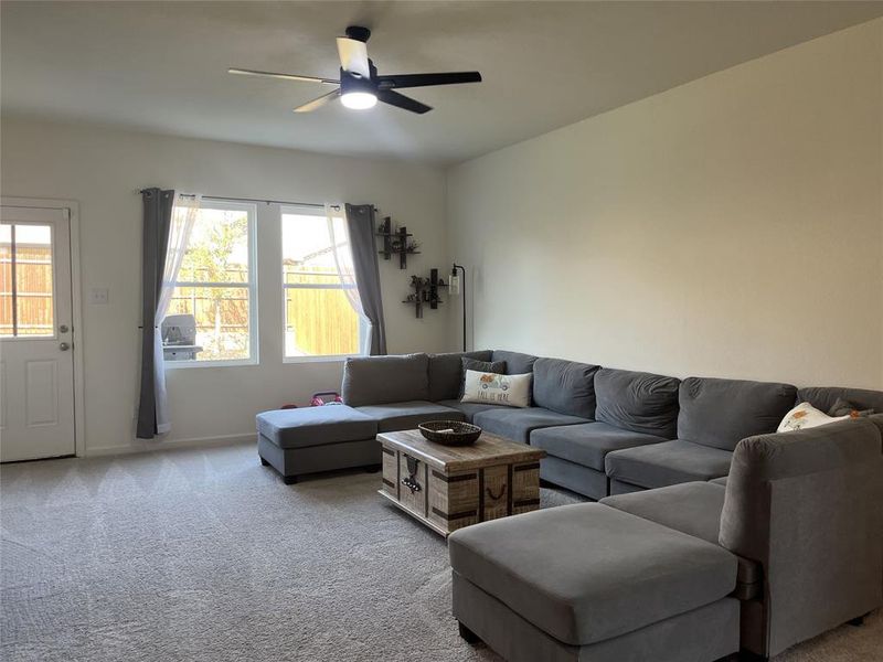 Living room featuring ceiling fan, light carpet, and plenty of natural light